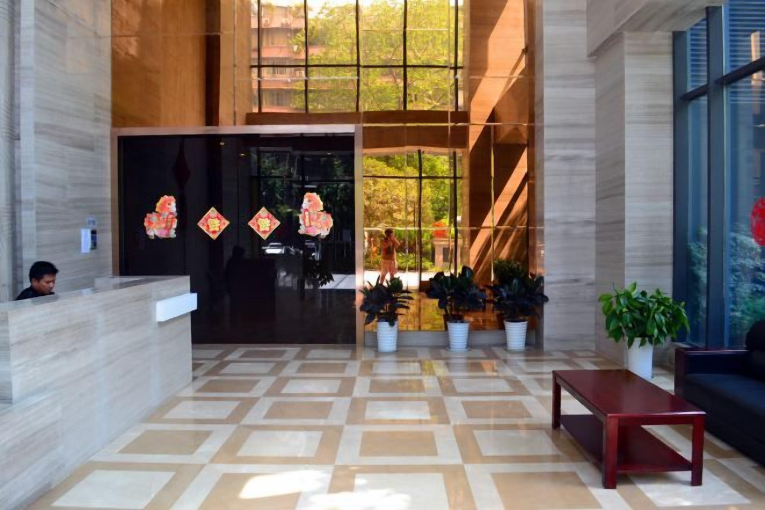 A lobby with a reception desk, potted plants, and a check-in counter.