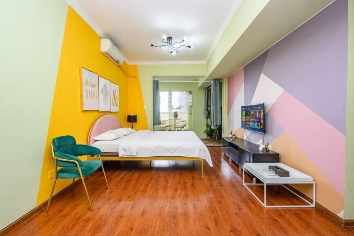 A bedroom with a bed, a chair, a TV, and a small table.