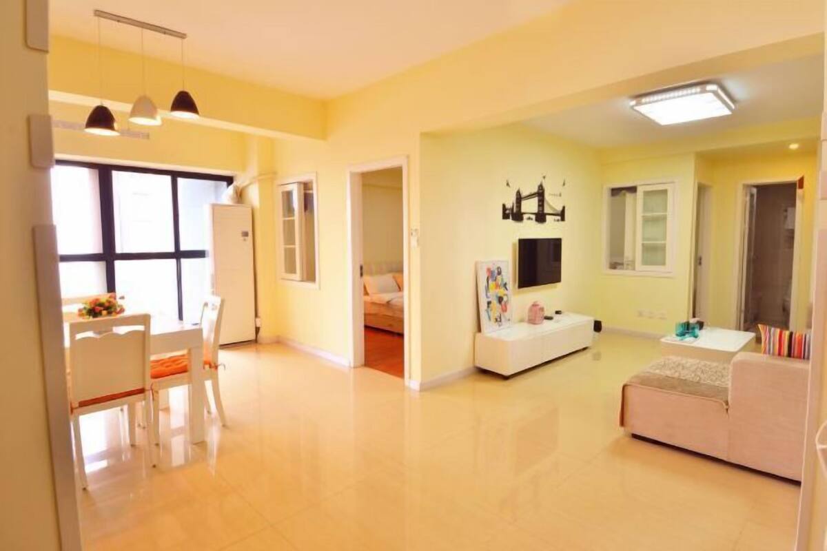 A spacious living area with a dining table, sofa, and TV.