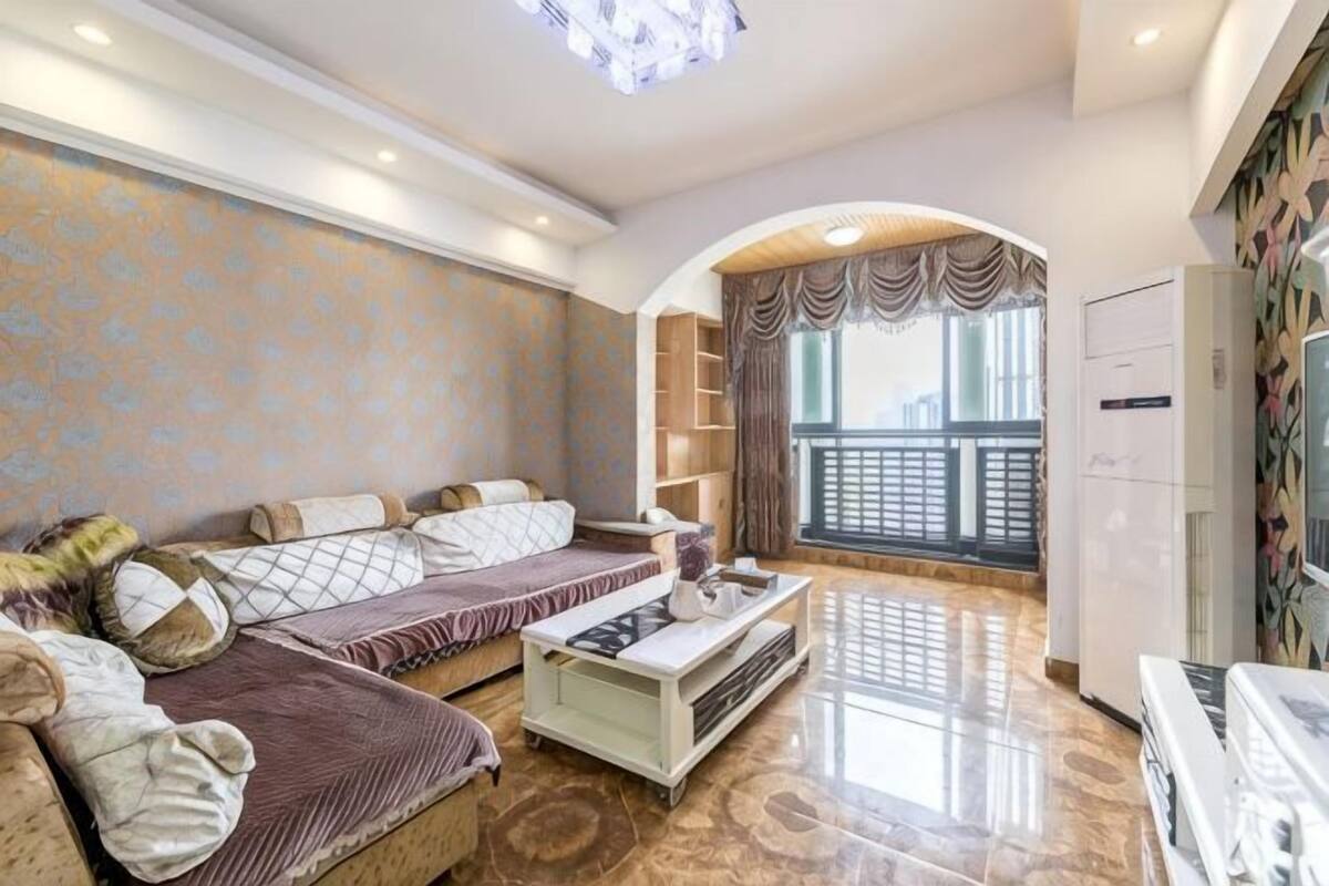 A living room with a sofa set, a coffee table, a TV, and a balcony with a railing.