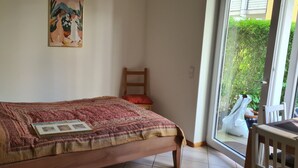 Une chambre à coucher avec un lit, une chaise, une fenêtre et un tableau accroché au mur.
