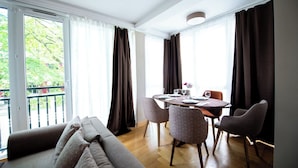 En matplats med ett bord för fyra personer, en soffa och utsikt genom stora fönster.
