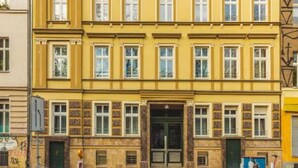 En byggnad med flera våningar, en gul fasad, stora fönster och en central entré.