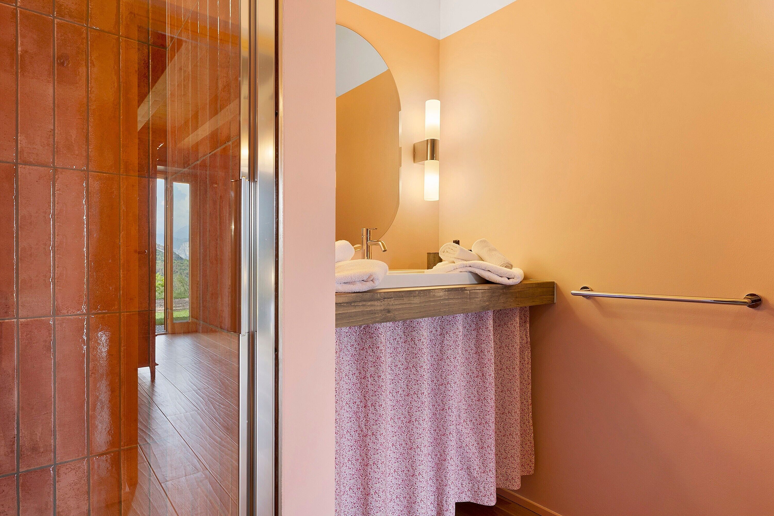 A bathroom with a shower, a sink with a towel rack, and a mirror.