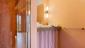 A bathroom with a shower, a sink with a towel rack, and a mirror.