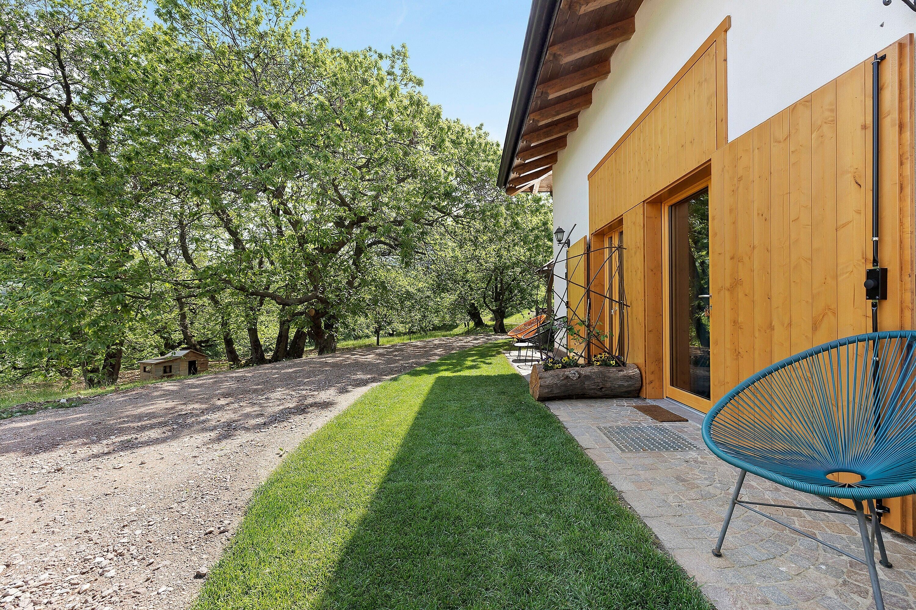 A house with a paved driveway, a lawn, and a blue chair outside.