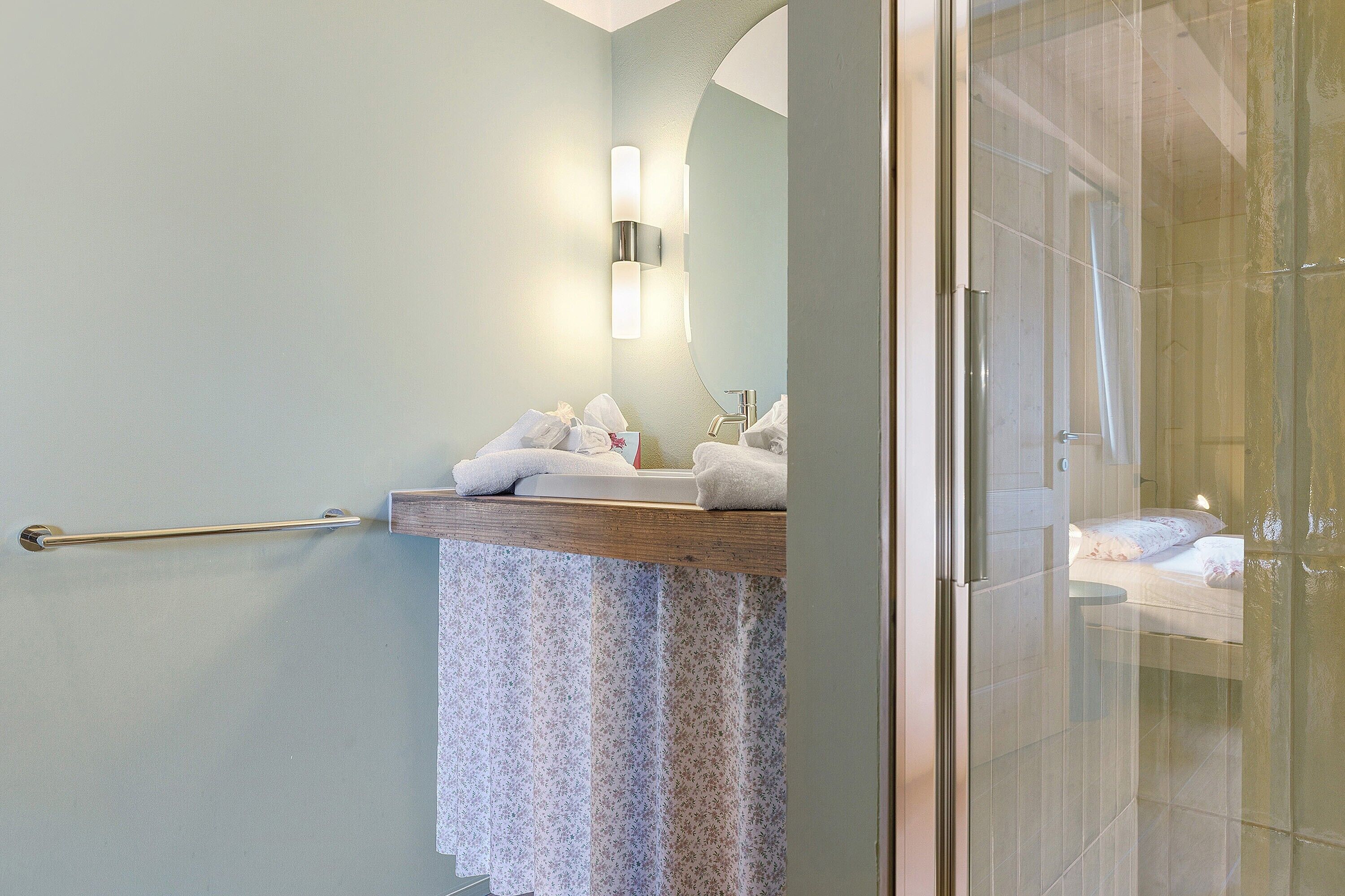 A bathroom with a towel rack, a sink, a mirror, and a shower area.