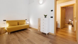 Una habitación moderna con un sofá, un tocador blanco y piso de madera.