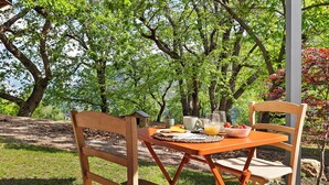 Mesa para comer al aire libre con sillas, un bol de fruta, una taza y un vaso de jugo.