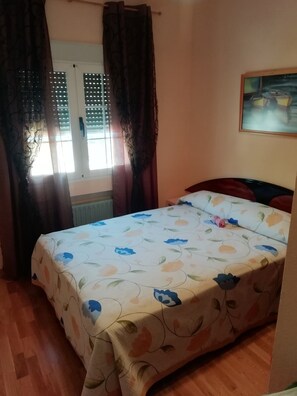 A bedroom with a bed, curtains, a window, and a painting on the wall. - Holiday Home 'Los Madroños' with Mountain View, Private Terrace and Private Garden (El Barraco)