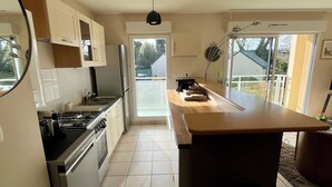 A modern kitchen with a central island, a stove, and a refrigerator. - Apartment in quiet, secure residence (Paimpol)