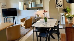 A modern living room with a TV, dining table, chairs, and a sofa. - Apartment in quiet, secure residence (Paimpol)