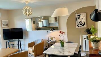 Un salon moderne comprenant un téléviseur, une table à manger, des chaises et un canapé.