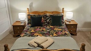 Una camera da letto con un letto di legno, due comodini con lampade, una luce a soffitto e una porta.