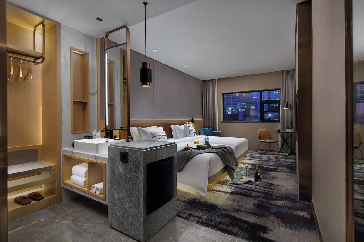 Una habitación de hotel moderna con una cama grande, un baño con tocador y vistas a la ciudad.