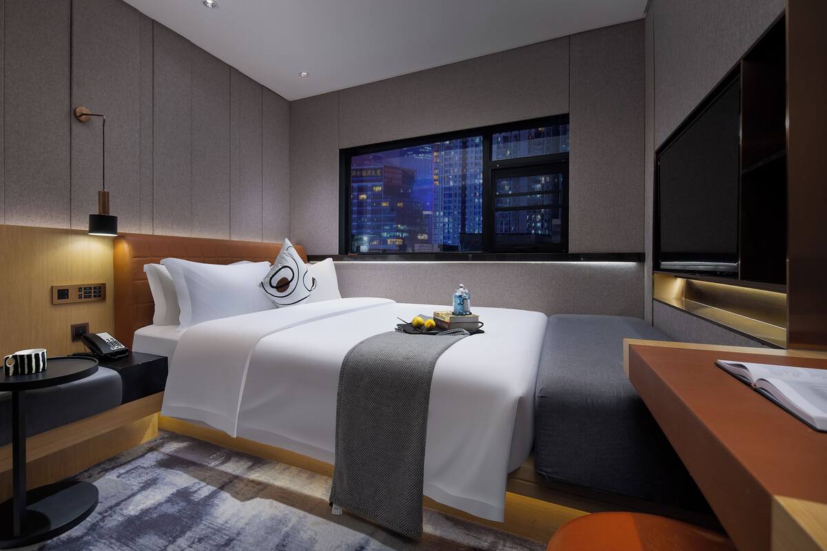 Una habitación de hotel moderna con una cama grande, una mesita de noche y un escritorio con una silla.