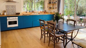 Une cuisine moderne avec des meubles de couleur bleue, une table à manger en bois et un four encastré.