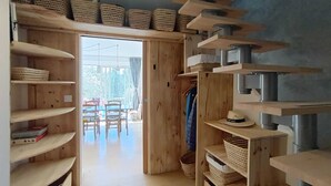 Une pièce avec des étagères en bois, des paniers et un coin repas comprenant des chaises et une table.