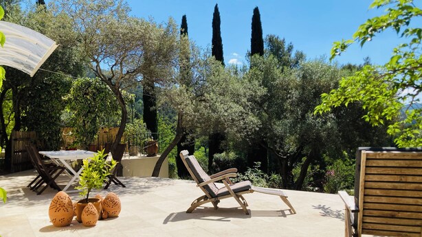 Une terrasse avec un fauteuil, une table et des plantes en pot.