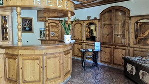 A reception desk with a wooden design, a potted plant, and a Singer sewing machine on a table. - Gasthof zur Post Weiding (Weiding)