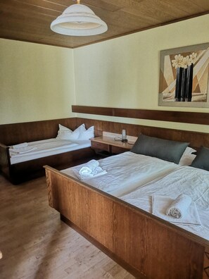 A hotel room with two beds, a wooden headboard, a bedside table, a lamp, and a painting on the wall. - Gasthof zur Post Weiding (Weiding)