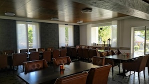 A spacious dining area with high ceilings, large windows, and a view of greenery outside. - Gasthof zur Post Weiding (Weiding)