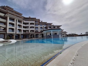 A modern hotel with a swimming pool, multiple balconies, and a covered area. - SoleMare by The Sea 2 bedroom apartment (Aheloy)