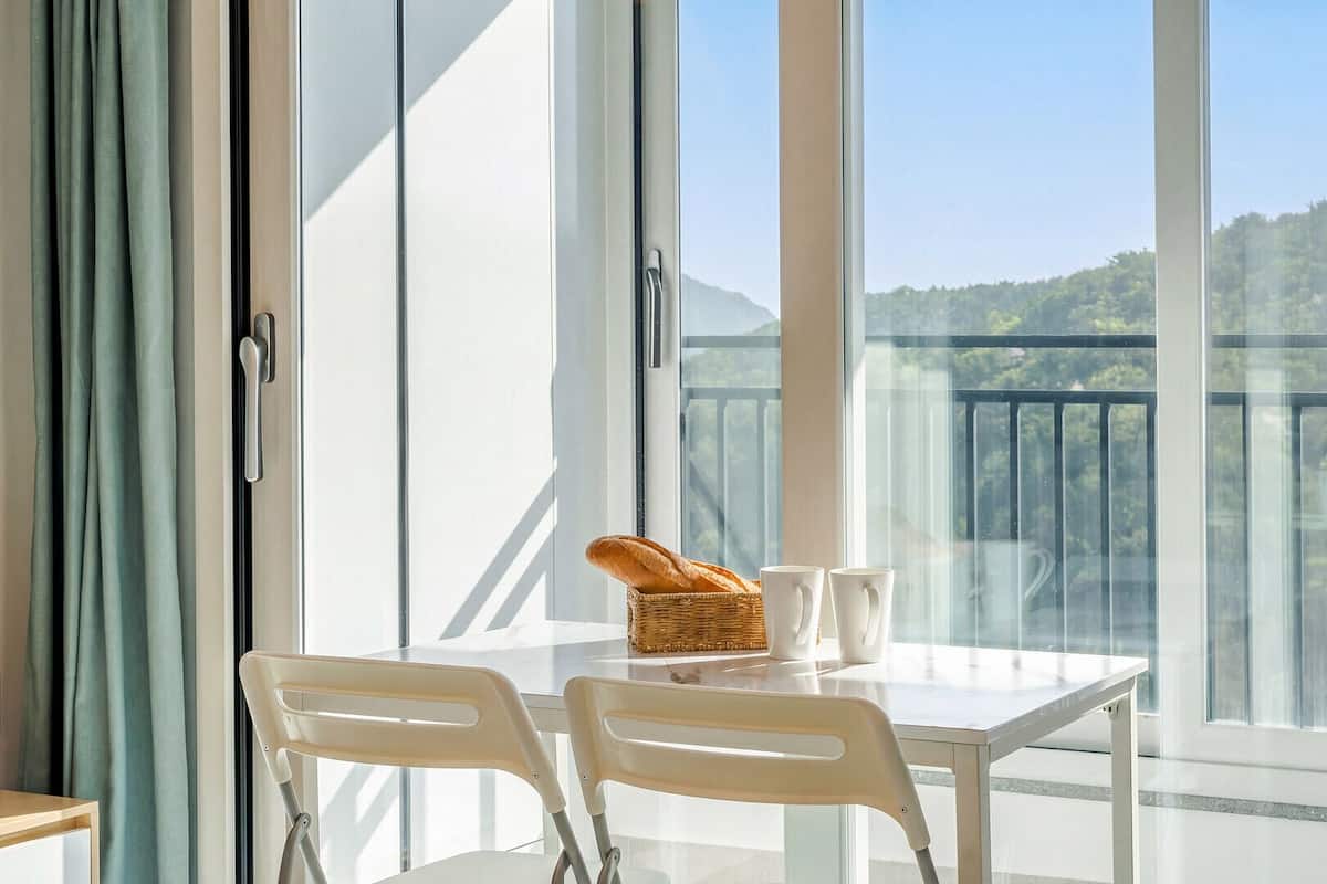 A balcony with a table, chairs, a basket, and two cups.