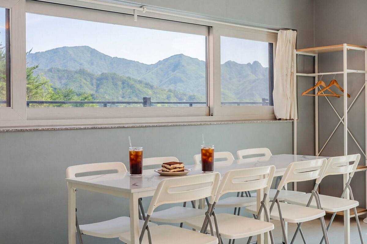A dining area with a table, chairs, and a view of mountains through large windows.