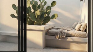 Una camera moderna con una porta scorrevole in vetro, una pianta di cactus, una panca imbottita e un lampadario a parete.