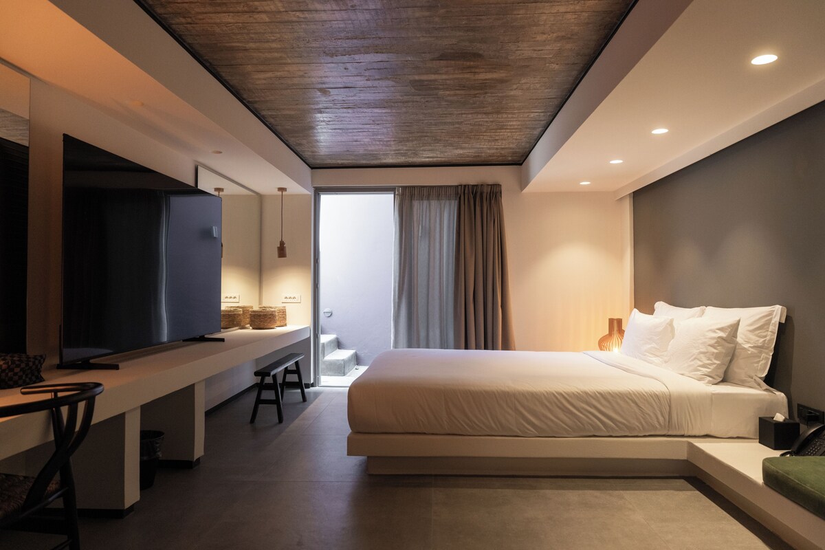 A modern hotel room with a large bed, a desk, and a television.