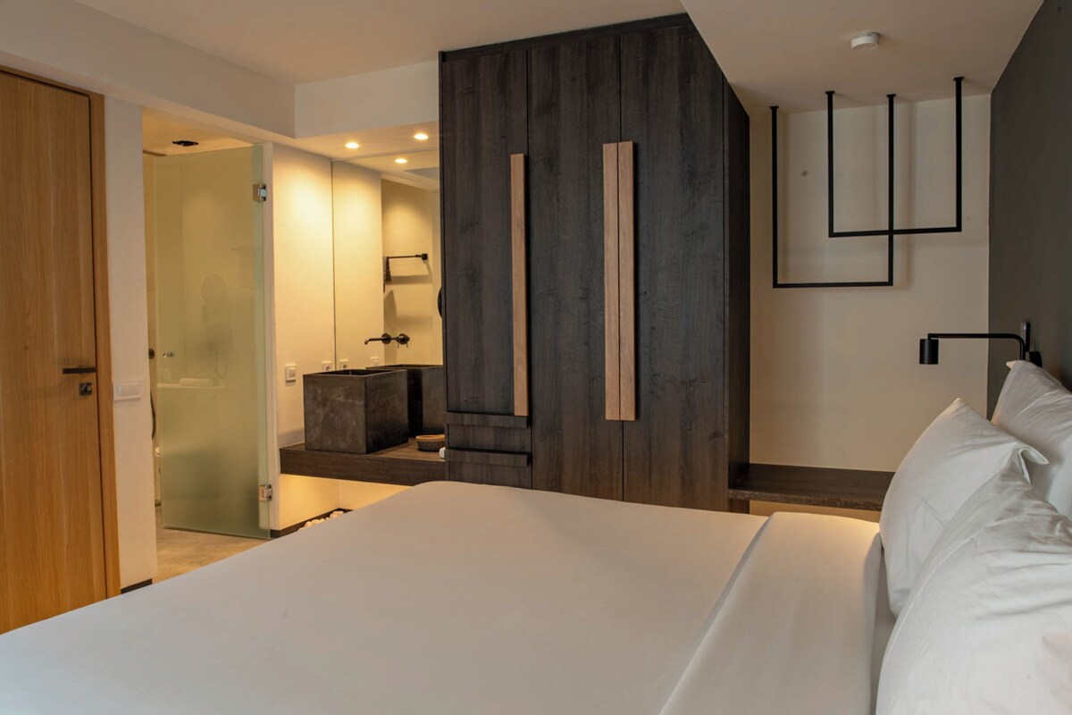 A modern bedroom with a large bed, a wooden accent wall, and a minimalist design.