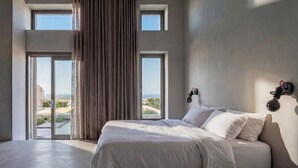 Camera da letto con un letto grande, due finestre, vista sull'esterno e un lampadario a parete.