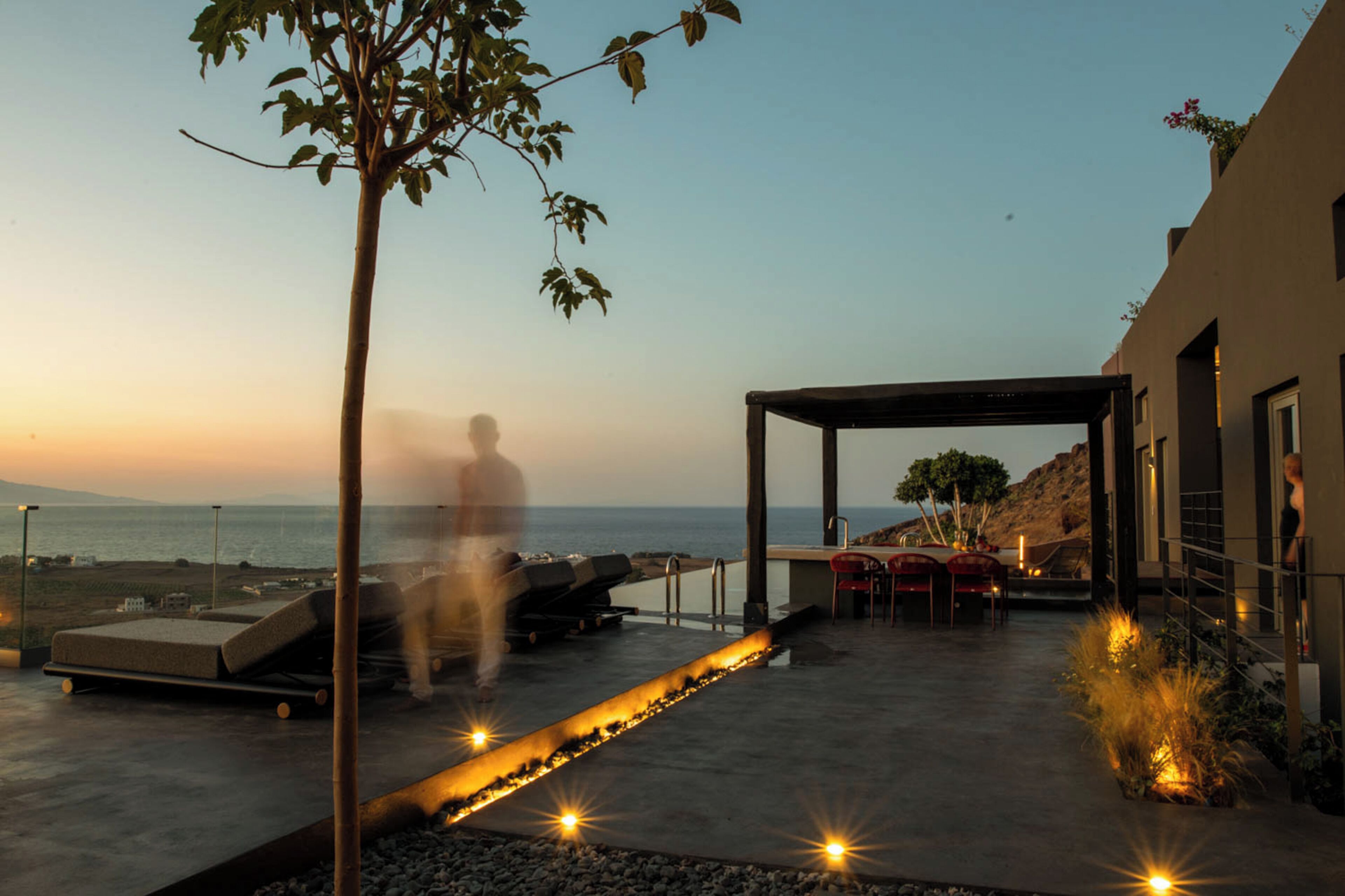 Terraço ao ar livre com piscina, área de estar e vista para o mar.