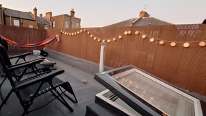 Eine Dachterrasse mit einer Hängematte, einem Picknicktisch und Lichterketten.