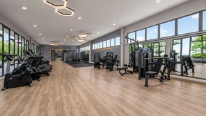 Una palestra con attrezzature per esercizi, ampie finestre e pavimento in legno.