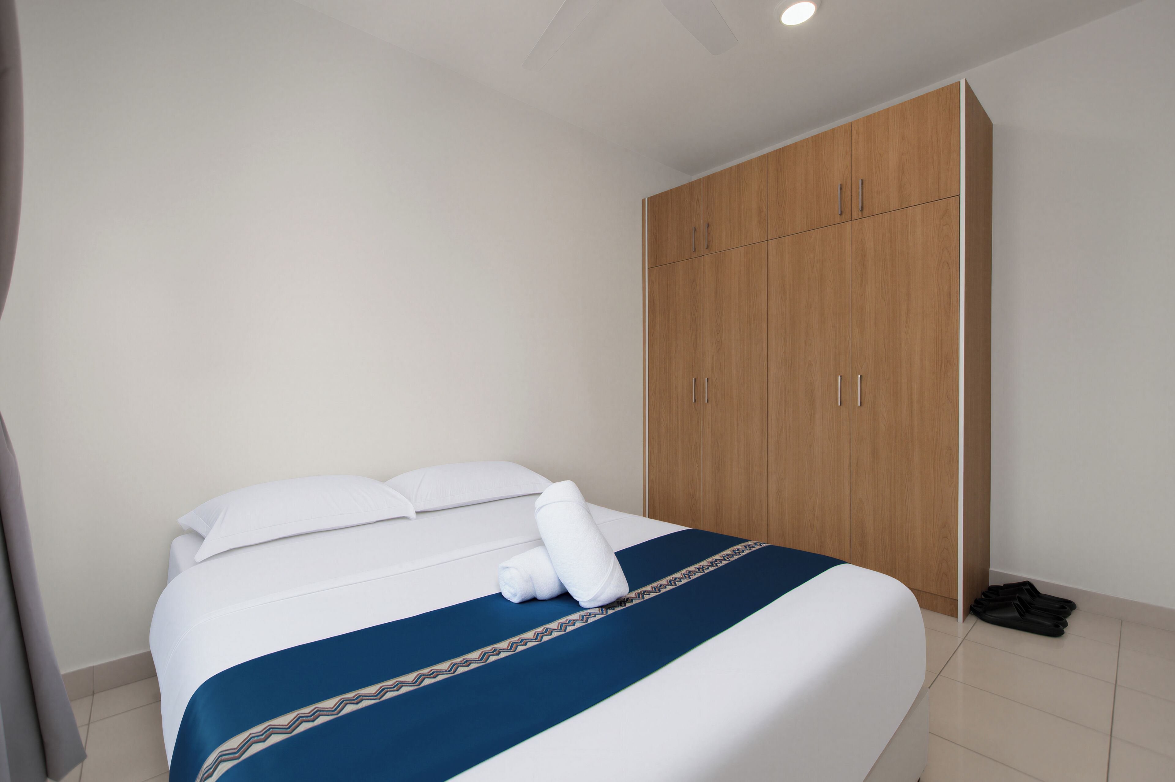 A hotel room with a bed, a wardrobe, and a suitcase on the floor.