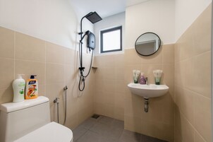 A small bathroom with a toilet, a shower, and a sink.