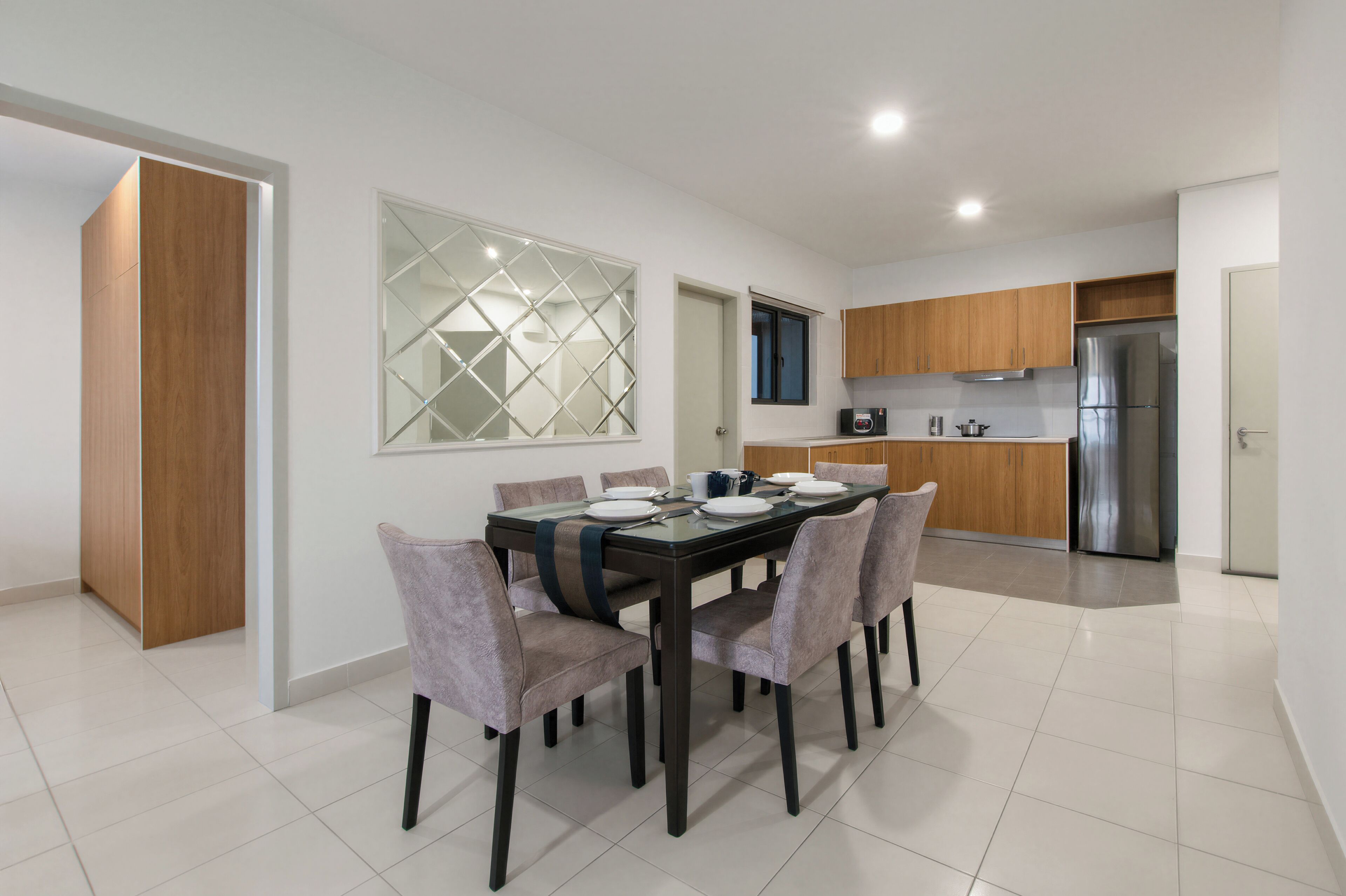 A modern kitchen with a dining area, featuring a large table, chairs, and a refrigerator.