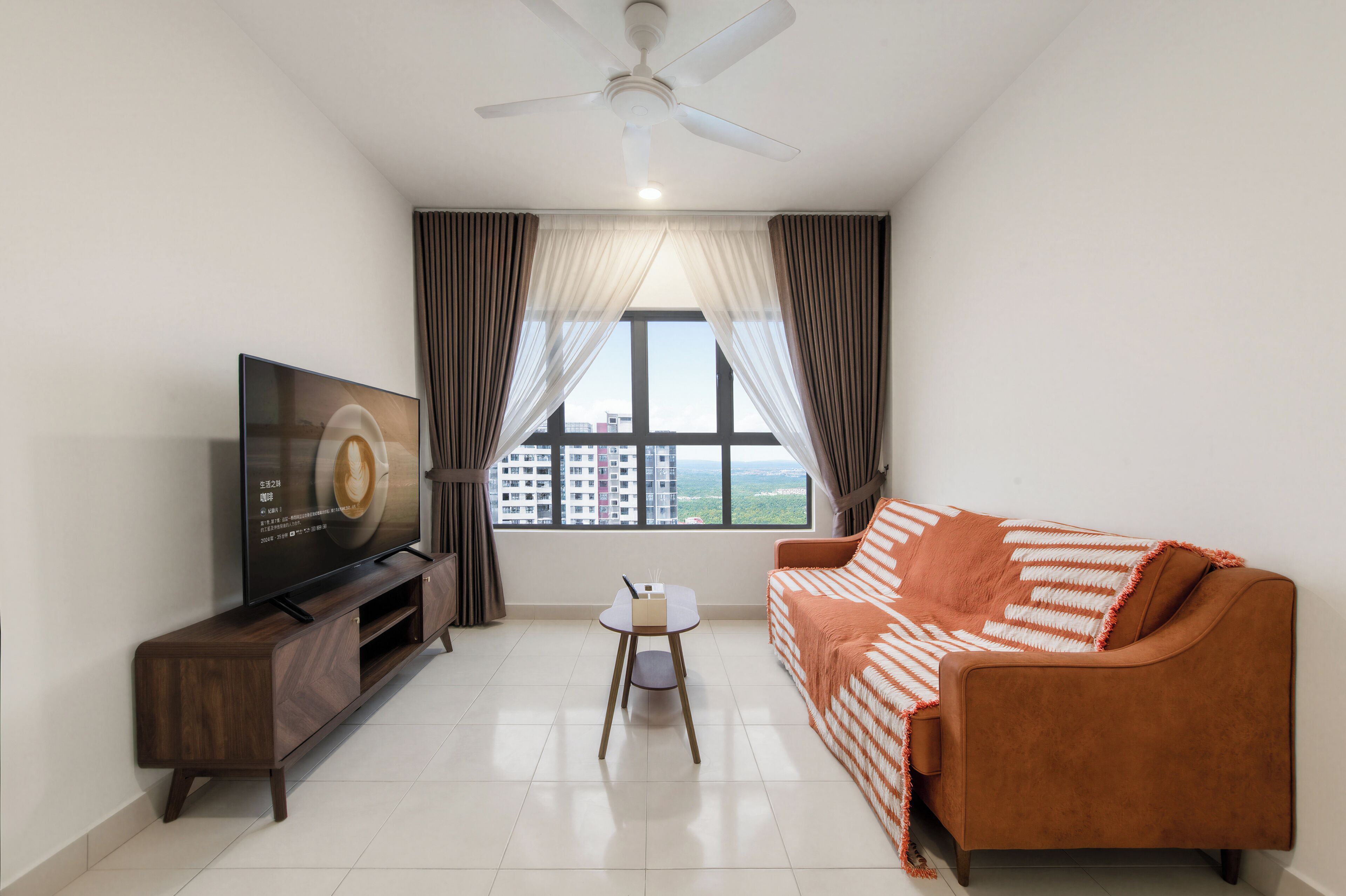A living room with a TV, a sofa, a small table, and a ceiling fan.