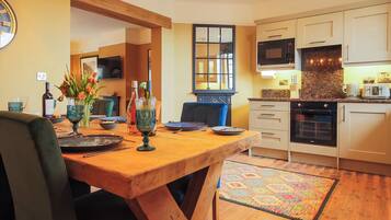 A modern kitchen with a wooden dining table, a TV, and a kitchen island.