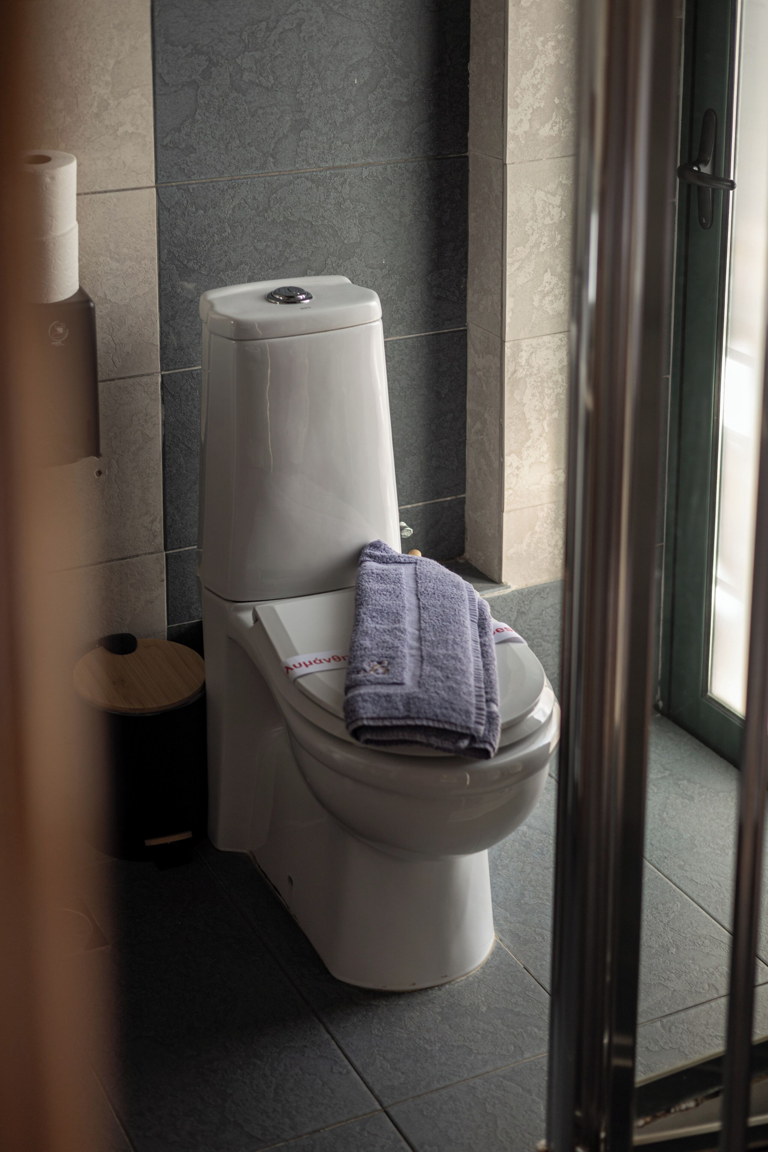 Uma casa de banho moderna com sanita, toalha e suporte para papel higiénico.