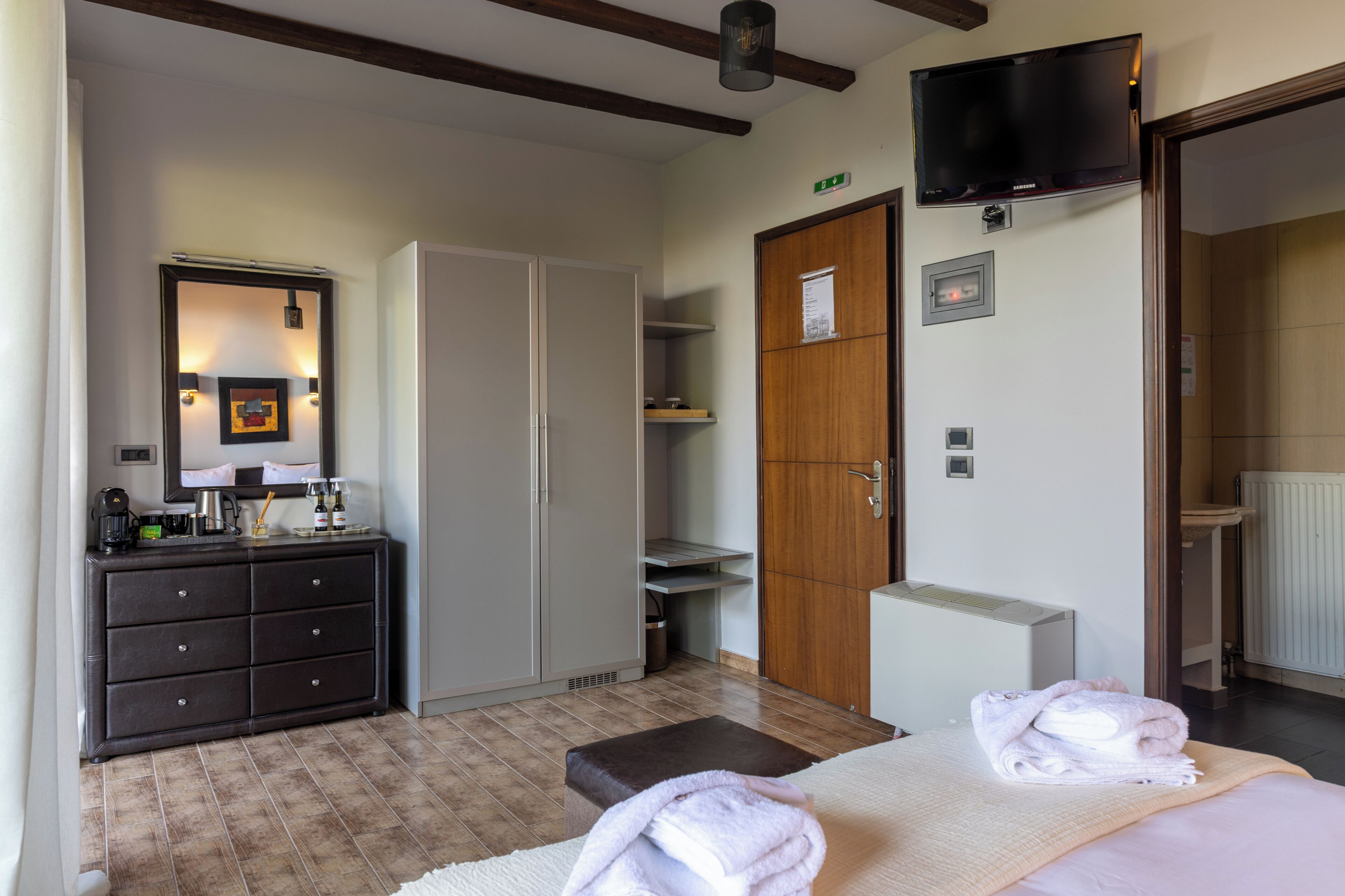 Hotellihuone, jossa on sänky, lipasto, vaatekaappi, televisio ja kylpyhuone.