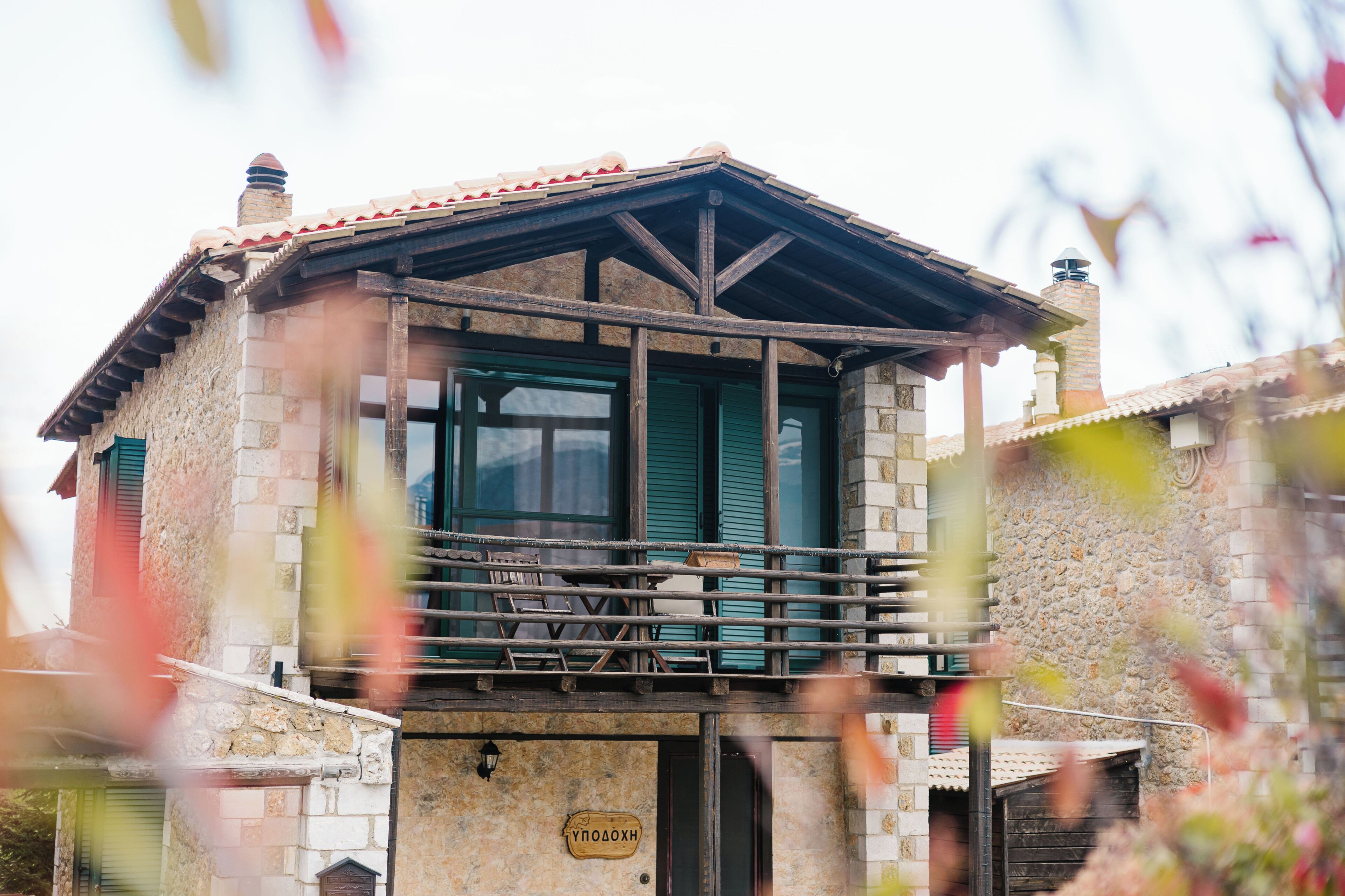 A stone building with a balcony, a chimney, and a sign with text.