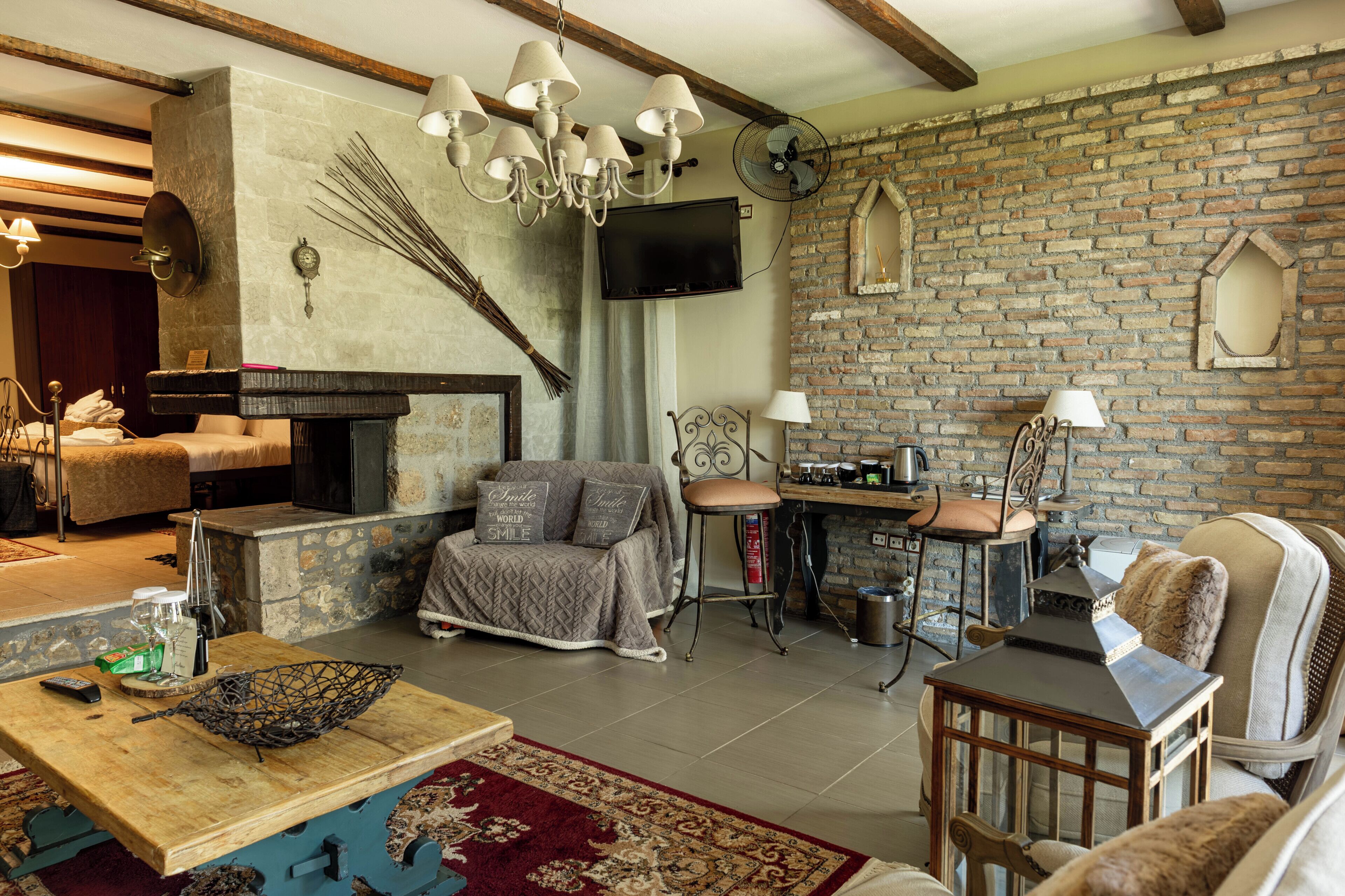 A cozy living room with a fireplace, a television mounted on the wall, and a rustic brick wall.