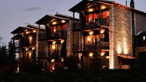 A multi-story building with balconies and warm lighting. - Vathyskia Guesthouse (Xylokastro-Evrostina)
