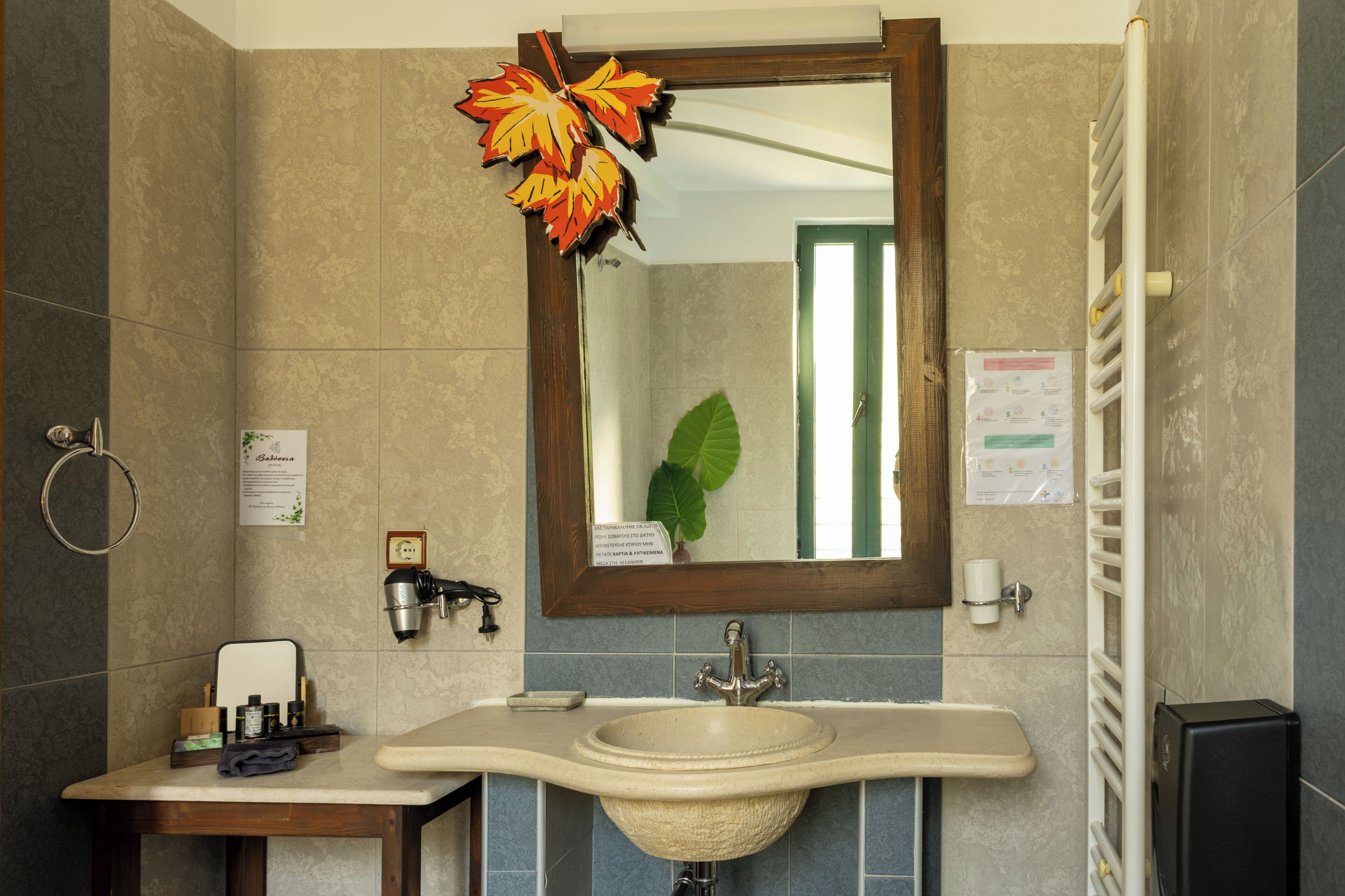 A bathroom with a sink, mirror, towel rack, and a decorative leaf.