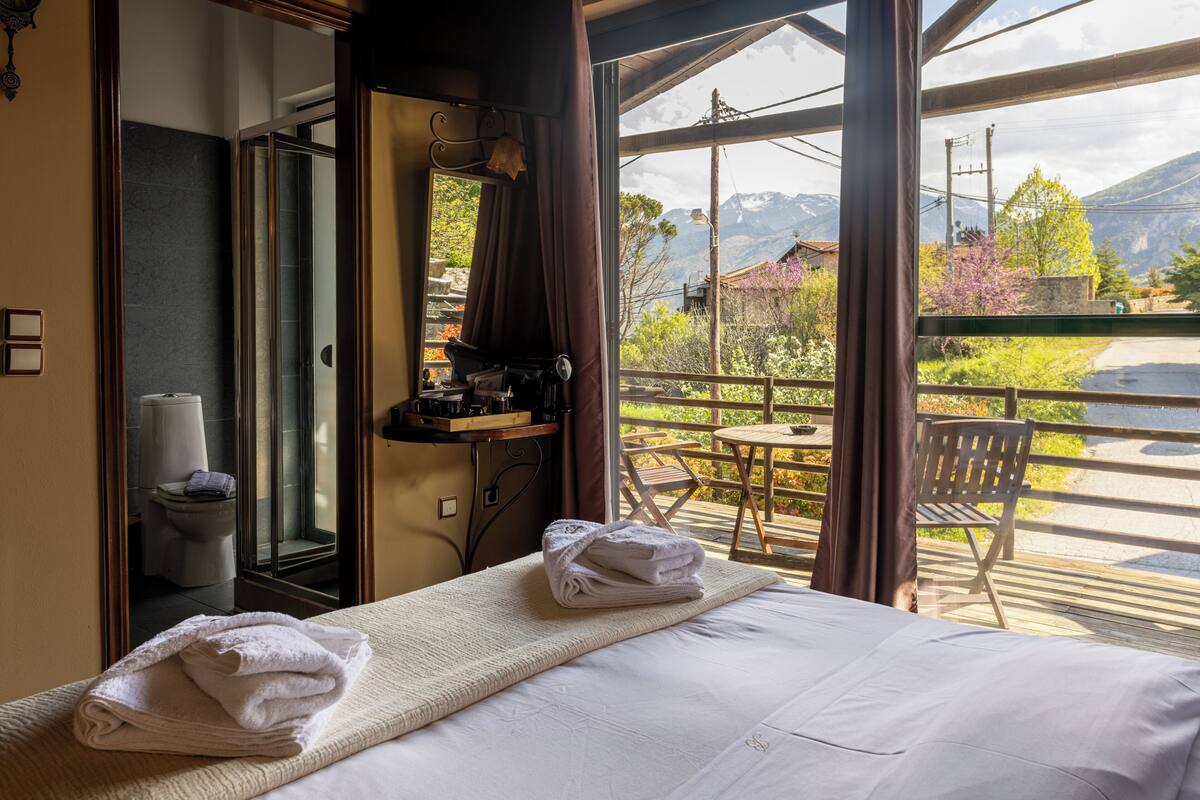 Ein Hotelzimmer mit Bett, Bad und einem Balkon mit Bergblick.