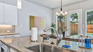 Cocina con encimera de granito, pileta de acero inoxidable y accesorios modernos.