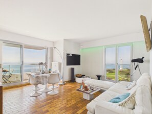 A spacious living room with a large window overlooking the sea, a dining area with modern furniture, and a cozy seating area with a white sofa. - Apartment with a magnificent sea view for 4 (Les Sables-d´Olonne)